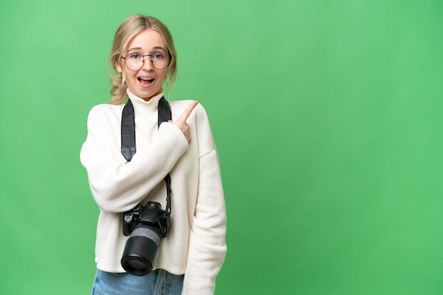 Junge Fotografin Engländerin vor isoliertem Hintergrund überrascht und zeigt zur Seite