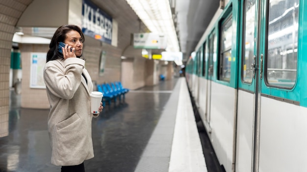 Foto junge französin wartet auf die u-bahn und spricht auf dem smartphone