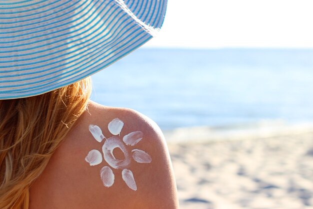 Junge Frau am Strand benutzt Sonnencreme