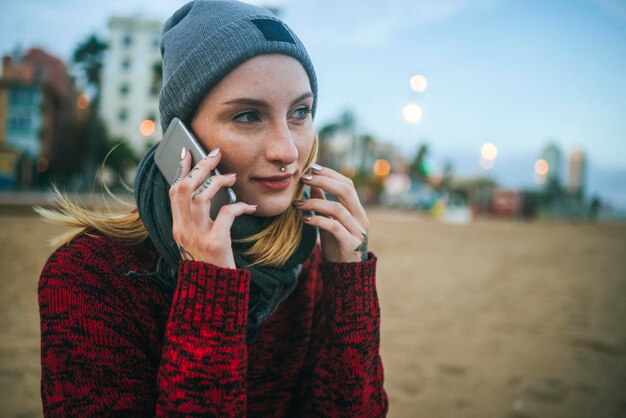 Junge Frau am Strand im Winter am Handy