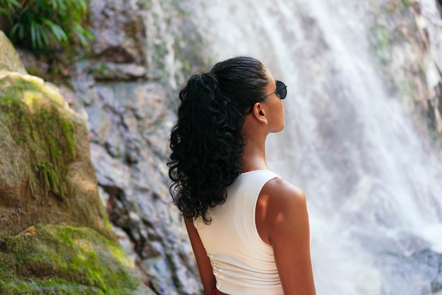 Junge Frau am unteren Rand eines tropischen Wasserfalls. Urlaubskonzept