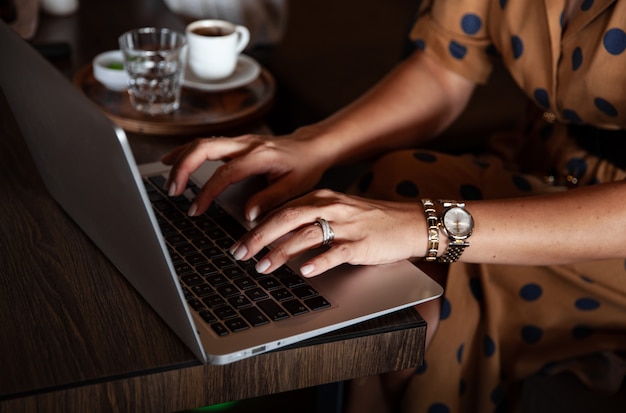 Junge Frau arbeitet am Computer und tippt auf Laptop im Coffeeshop