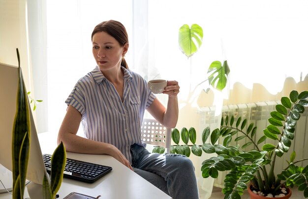 Junge Frau arbeitet an einem Desktop-Computer zu Hause in Quarantäne