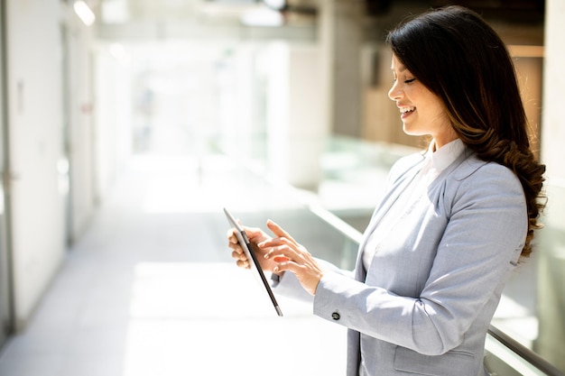 Junge Frau arbeitet an einem digitalen Tablet im Büroflur