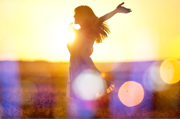 Junge Frau auf dem Feld unter Sonnenuntergangslicht