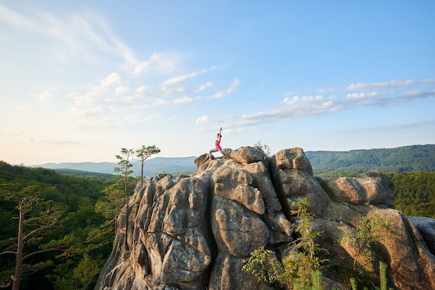 Junge Frau auf einer Klippe in einer Yoga-Pose