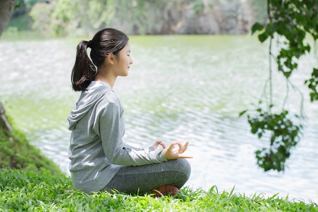 Junge Frau auf einer Yogamatte, zum im Park zu entspannen. Entspannen Sie in der Natur