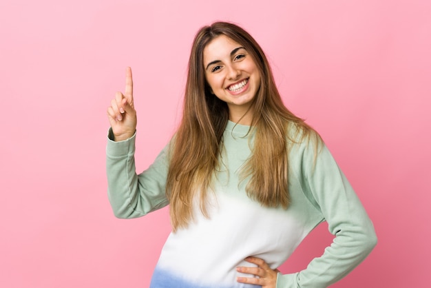 Junge Frau auf isoliertem Rosa, das einen Finger im Zeichen des Besten zeigt und hebt