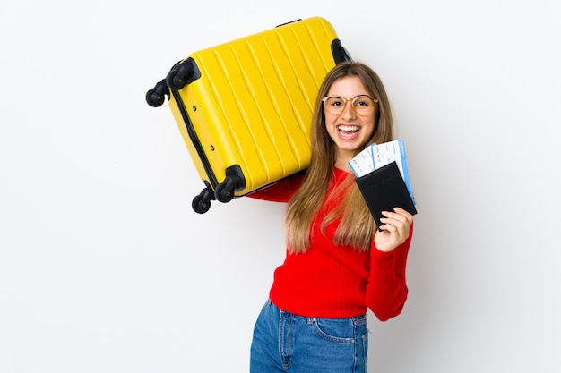 Junge Frau auf isoliertem Weiß im Urlaub mit Koffer und Pass