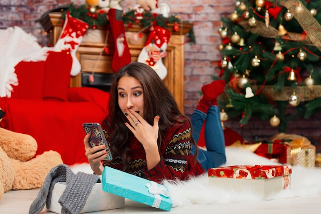 Junge Frau auf Quarantäne, die Videoanrufe auf dem Hintergrund der Weihnachtsdekorationen spricht