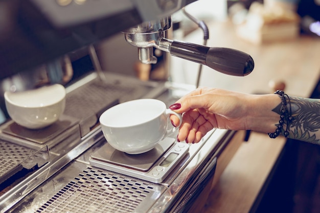 Junge Frau Barista mit Kaffeemaschine im Café