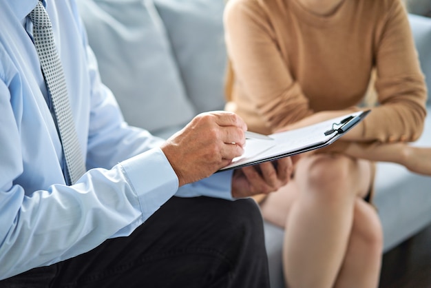 Junge Frau bei einer Konsultation mit einem Psychotherapeuten. Die Psychologin hat eine Sitzung mit ihrer Patientin im Büro und gibt ihm Ratschläge über sein Leben