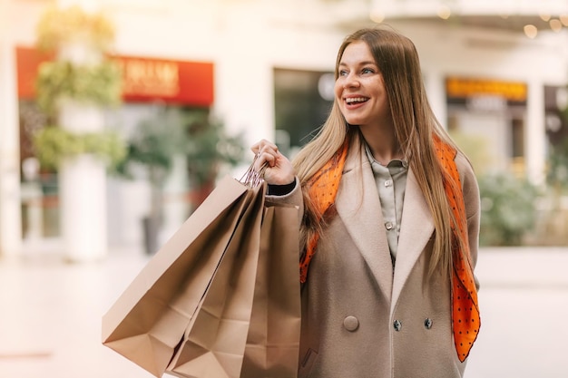 Junge Frau beim Einkaufen Glückliche Frau mit Einkaufstüten beim Einkaufen