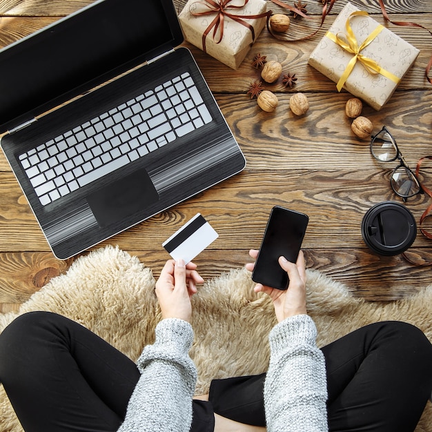 Foto junge frau beim einkaufen und kaufen von geschenken mit laptop, smartphone und kreditkarten