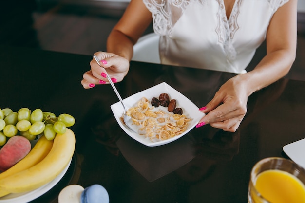 Junge Frau beim Frühstück mit Müsli und Milch