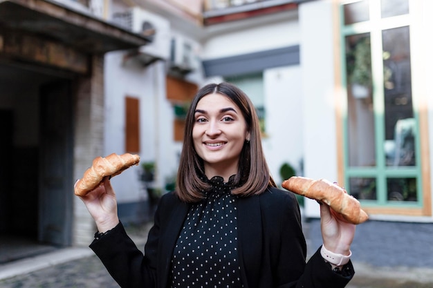 Junge Frau beim Frühstück und lächelnd Croissants essen Frühstück Das Mädchen isst ein Croissant Junge Frau isst Croissants in einem Café