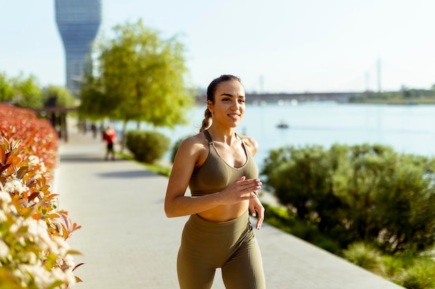 Junge Frau beim Lauftraining an der Flusspromenade