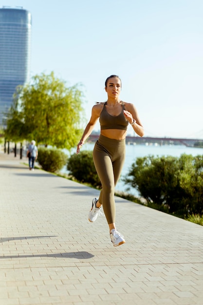 Junge Frau beim Lauftraining an der Flusspromenade