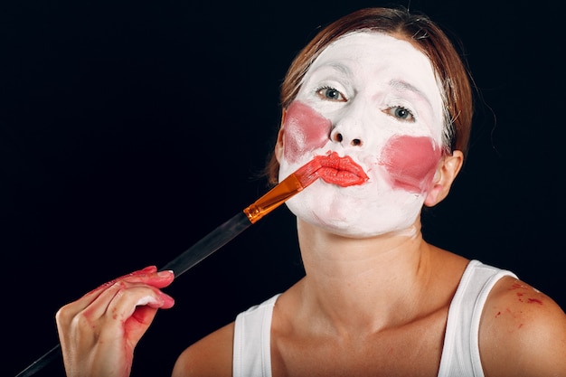 Junge Frau beim Schminken, malt Gesicht mit Pinsel und Make-up. Wie man kein Make-up-Konzept macht.