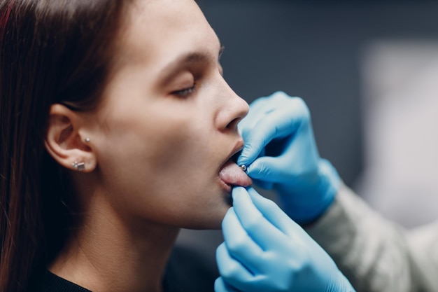 Junge Frau beim Tonque-Piercing im Schönheitsstudio-Salon