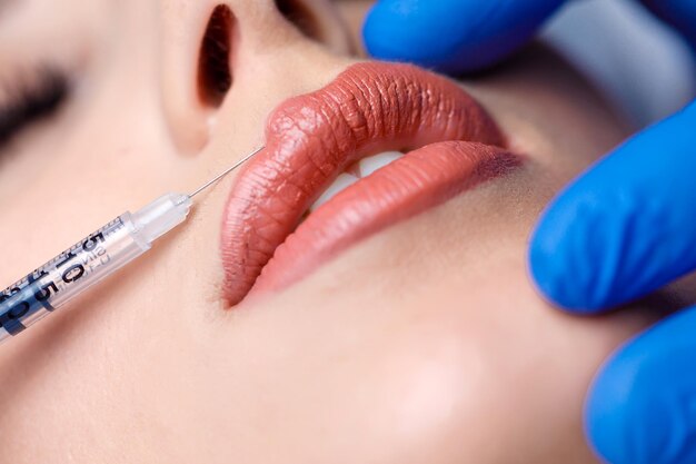 Junge Frau bekommt Botox-Injektion in ihre Lippen. Frau im Schönheitssalon. Klinik für plastische Chirurgie.