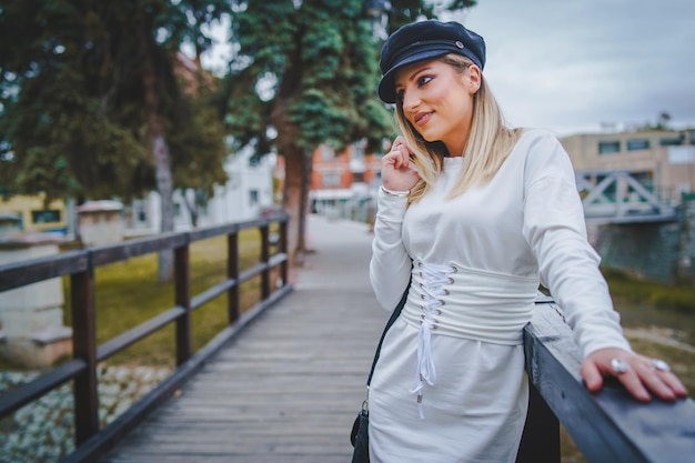 Foto junge frau benutzt das telefon, während sie am geländer der fußgängerbrücke steht