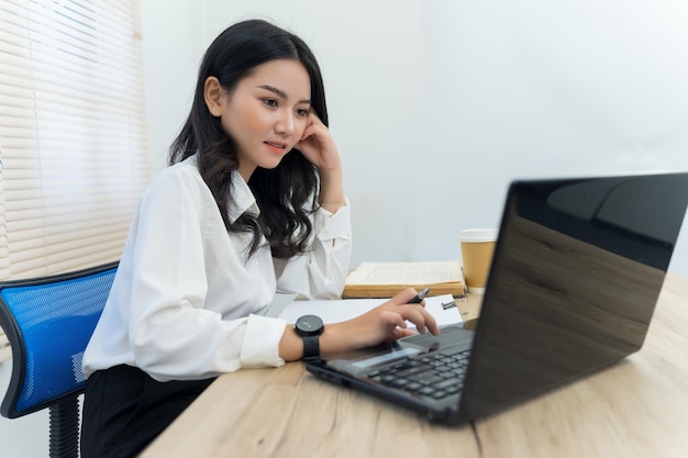 Junge Frau benutzt das Telefon, während sie auf dem Tisch sitzt