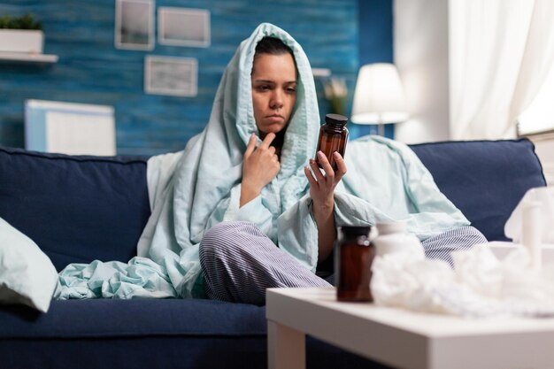 Junge Frau benutzt das Telefon, während sie zu Hause auf dem Sofa sitzt