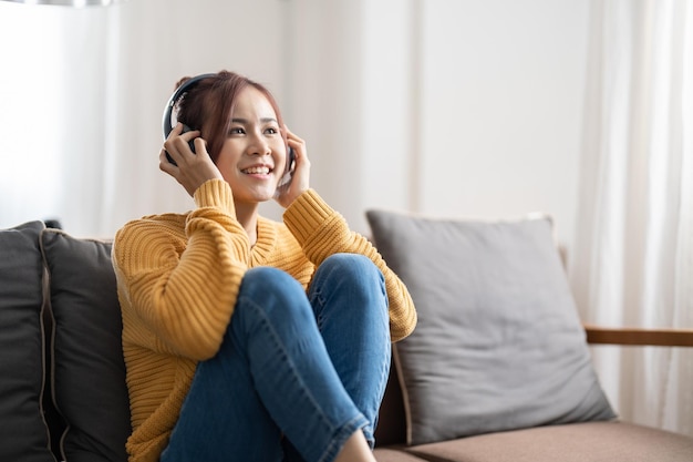 Junge Frau benutzt das Telefon, während sie zu Hause auf dem Sofa sitzt