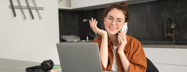 Foto junge frau benutzt ein handy, während sie auf einem tisch sitzt