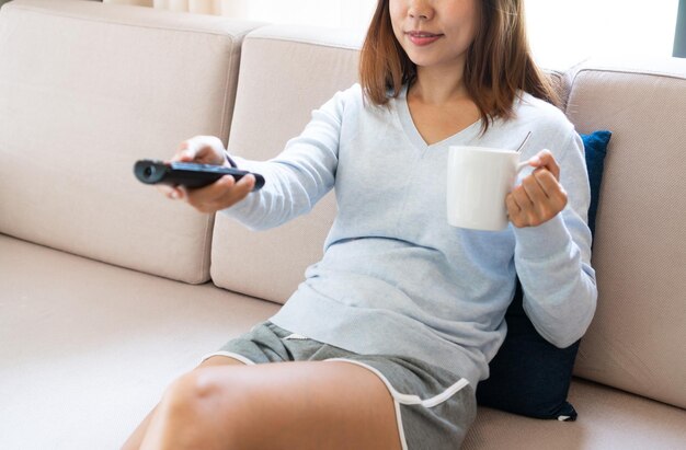 Foto junge frau benutzt ein handy, während sie zu hause auf dem sofa sitzt