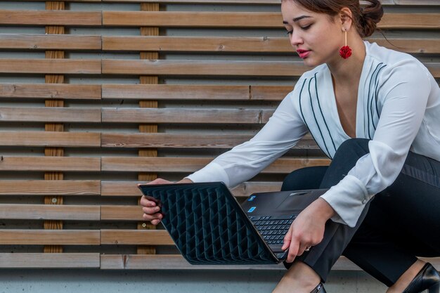 Foto junge frau benutzt einen laptop auf dem gehweg