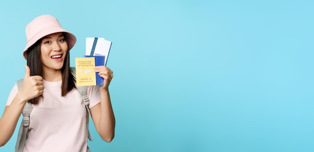 Junge Frau benutzt Handy vor blauem Hintergrund