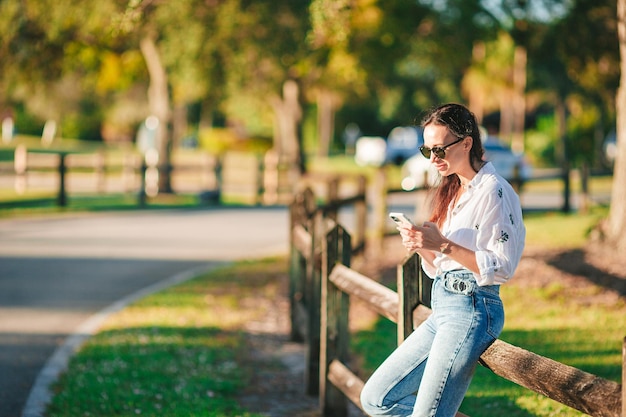 Junge Frau benutzt im Park im Freien ein Handy