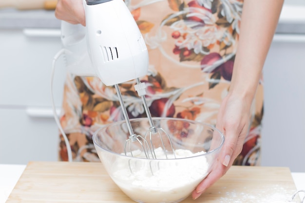 Junge Frau benutzt Mixer beim Eierschlagen, steht in einer modernen Küche