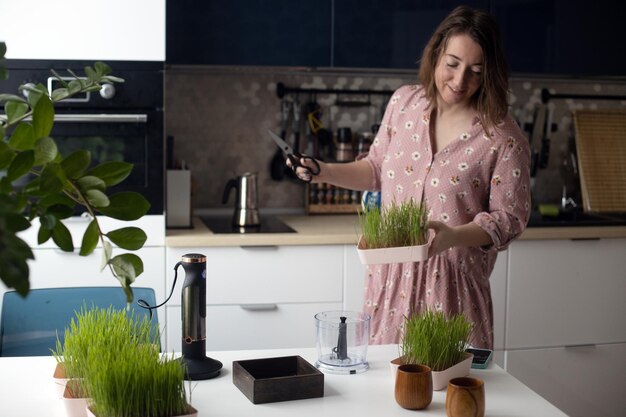 Foto junge frau bereitet grünen weizengrassaft zu und hat spaß beim tanzen eines gesunden antioxidativen getränks