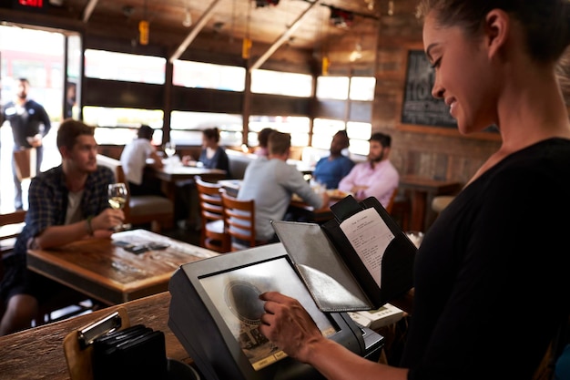 Junge Frau bereitet Rechnung im Restaurant mit Touchscreen vor
