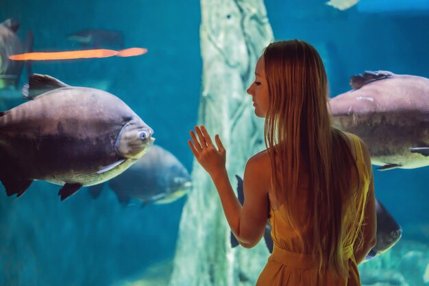 Junge Frau berührt einen Stachelrochen in einem Ozeanarium-Tunnel