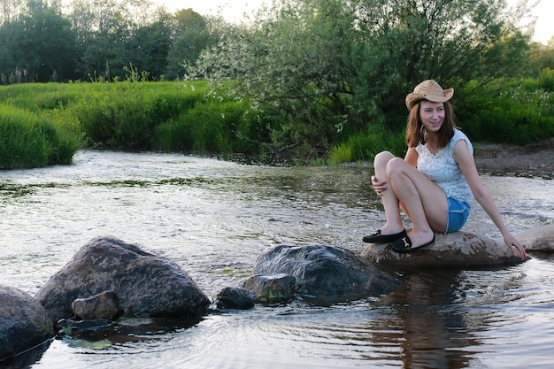 Junge Frau bewundert den Sonnenuntergang am Frühlingsabend am Fluss