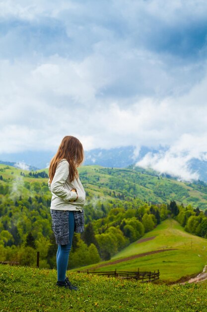 Junge Frau blickt auf wunderbare Aussicht auf die Berglandschaft mit Wald und Nebel darüber