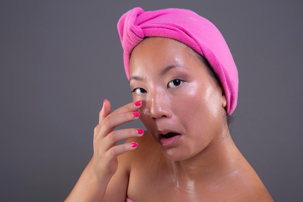 Junge Frau chinesischer Abstammung, die sich mit Gesichtscreme um ihr Gesicht kümmert