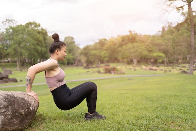 Junge Frau der asiatischen Tätowierung, die Yoga im Park tut