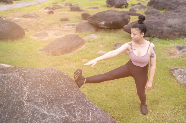 Junge Frau der asiatischen Tätowierung, die Yoga im Park tut