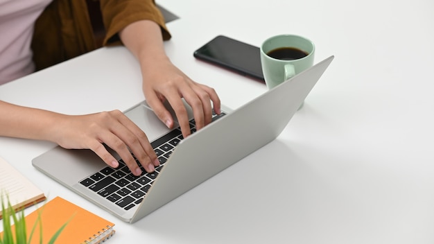 Junge Frau der Nahaufnahme, die Laptop-Computer auf Bürotisch- und Kopienraum verwendet.