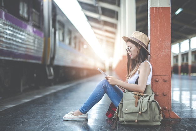 Junge Frau der Reisenden mit dem Rucksack, der hält, halten eine Karte an der Bahnstation. Tourismus Tag.