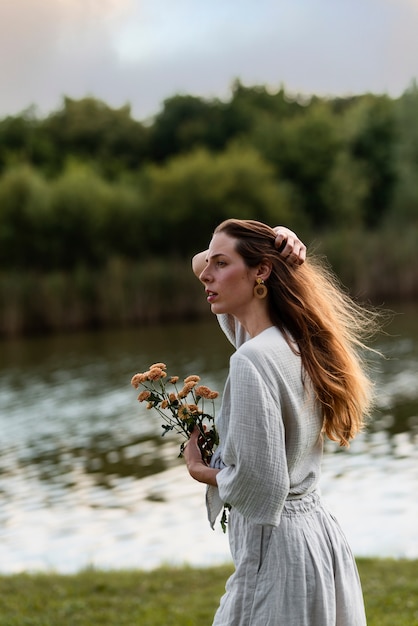 Junge Frau der Seitenansicht, die Blumen hält