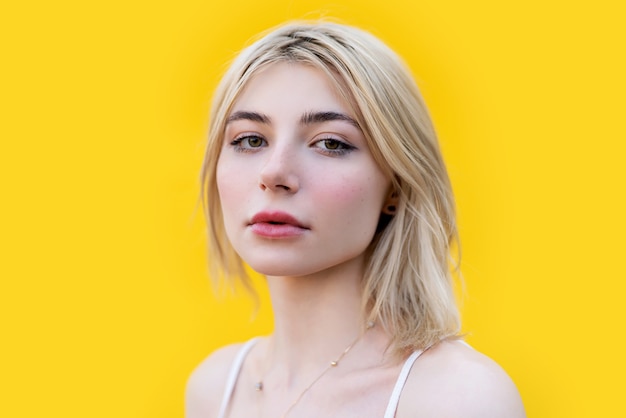 Junge Frau des Mädchens auf einem hellen gelben Wandhintergrundstudioporträt