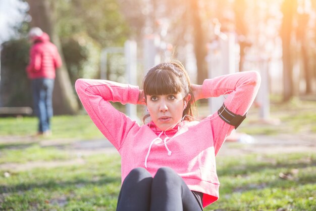 Junge Frau, die ABS-Übungen am Park tut.