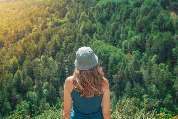 Junge Frau, die allein draußen mit wilden Waldbergen im Hintergrund steht