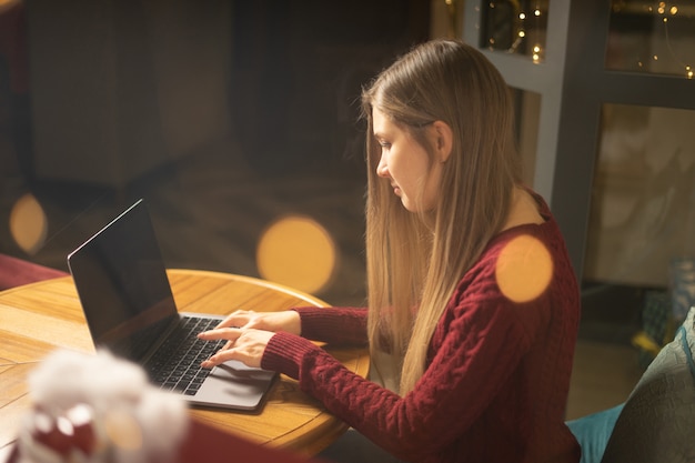 Junge Frau, die am Abend das Internet am Café durchstöbert